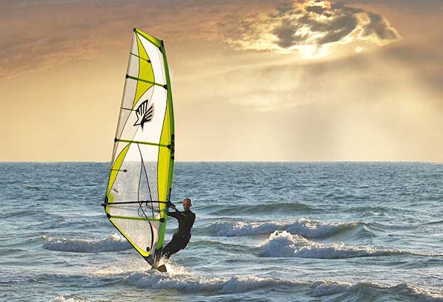 uomo con il windsurf in mare al tramonto in versilia