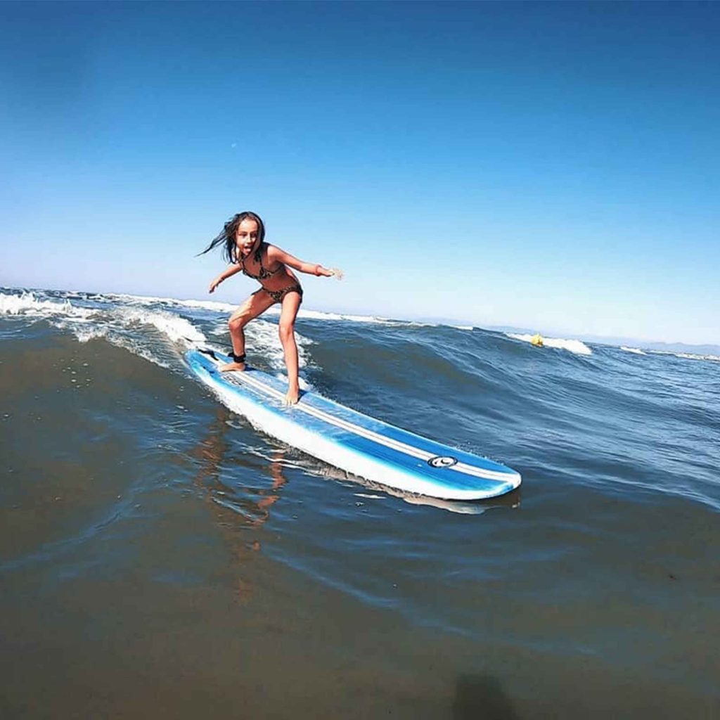 bambina che cavalca le onde in surf in versilia